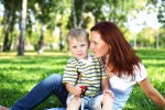 Mom holding young son in green grass