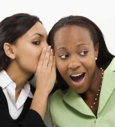 Woman whispering in the ear of another