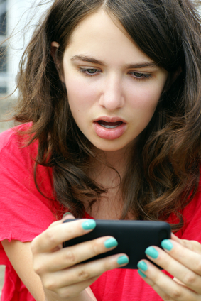 Teenaged girl looking at cell in disbelief