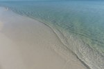 Clear blue water reaches the pure white sand