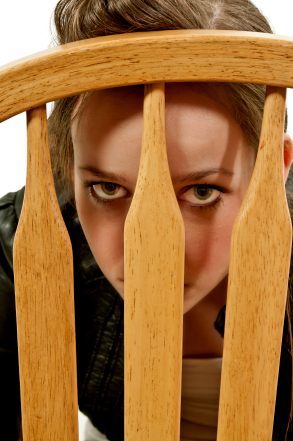 Woman looking thru back of chair