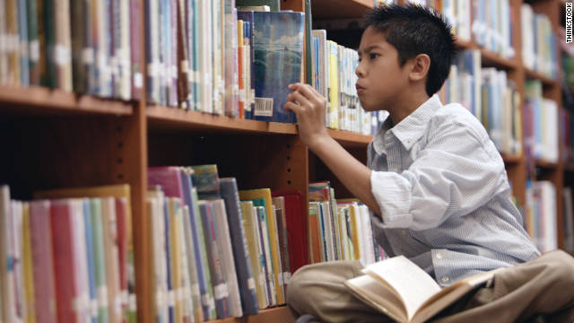 Boy pulling book from library shelf