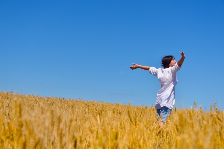 Woman in wheat field arms out-stretched