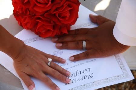 Bride and groom hands on marriage certificate