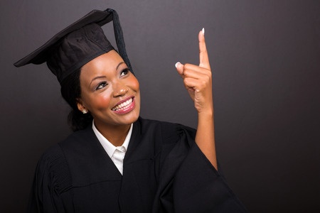 Young lady in cap and gown pointing upward