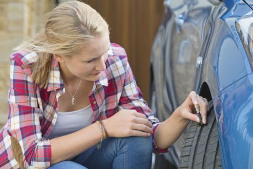 Woman Checking Tread Depth On Car Tyre